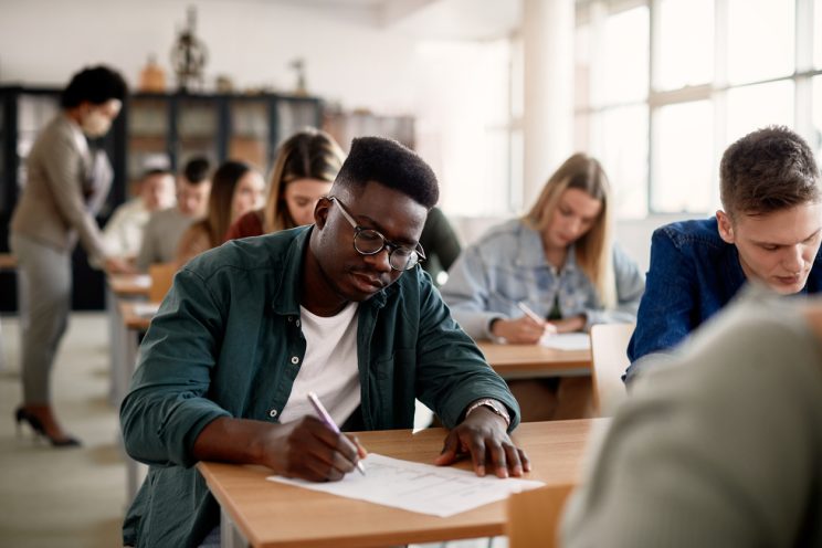 Student writing at a desk in a classroom 