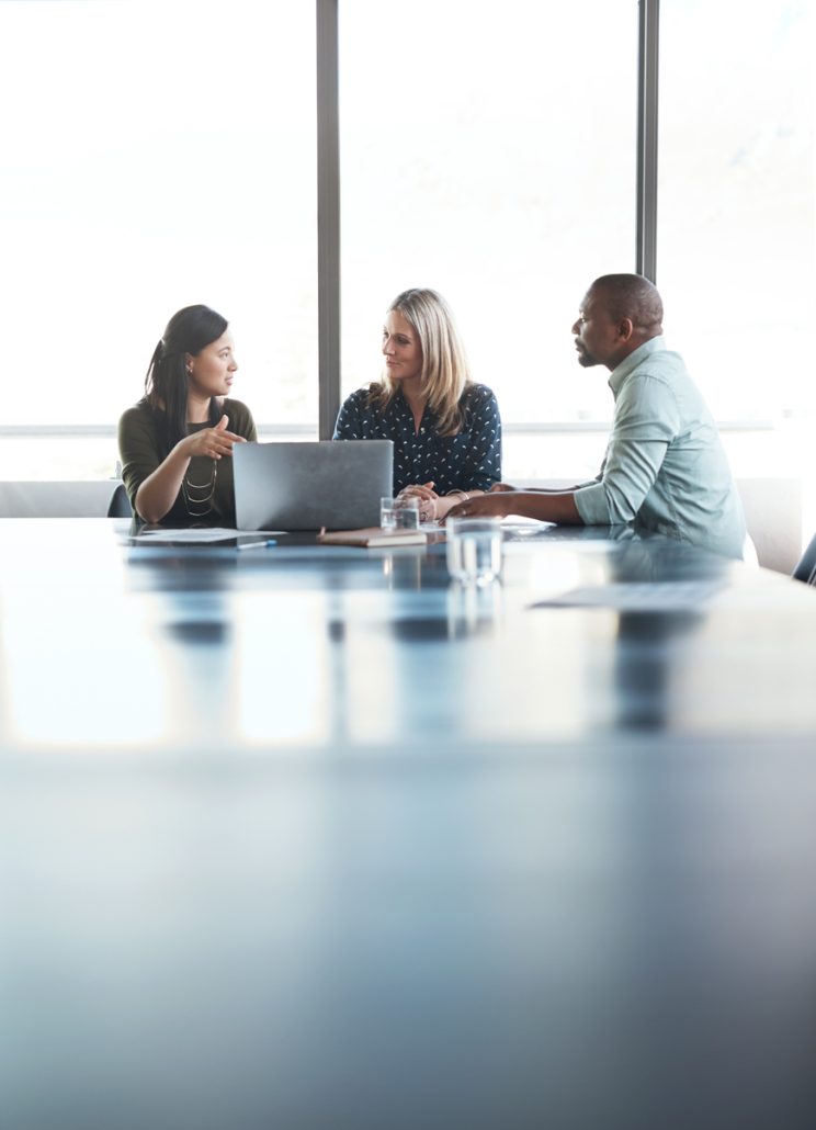 A meeting among coworkers at a table with a computer 